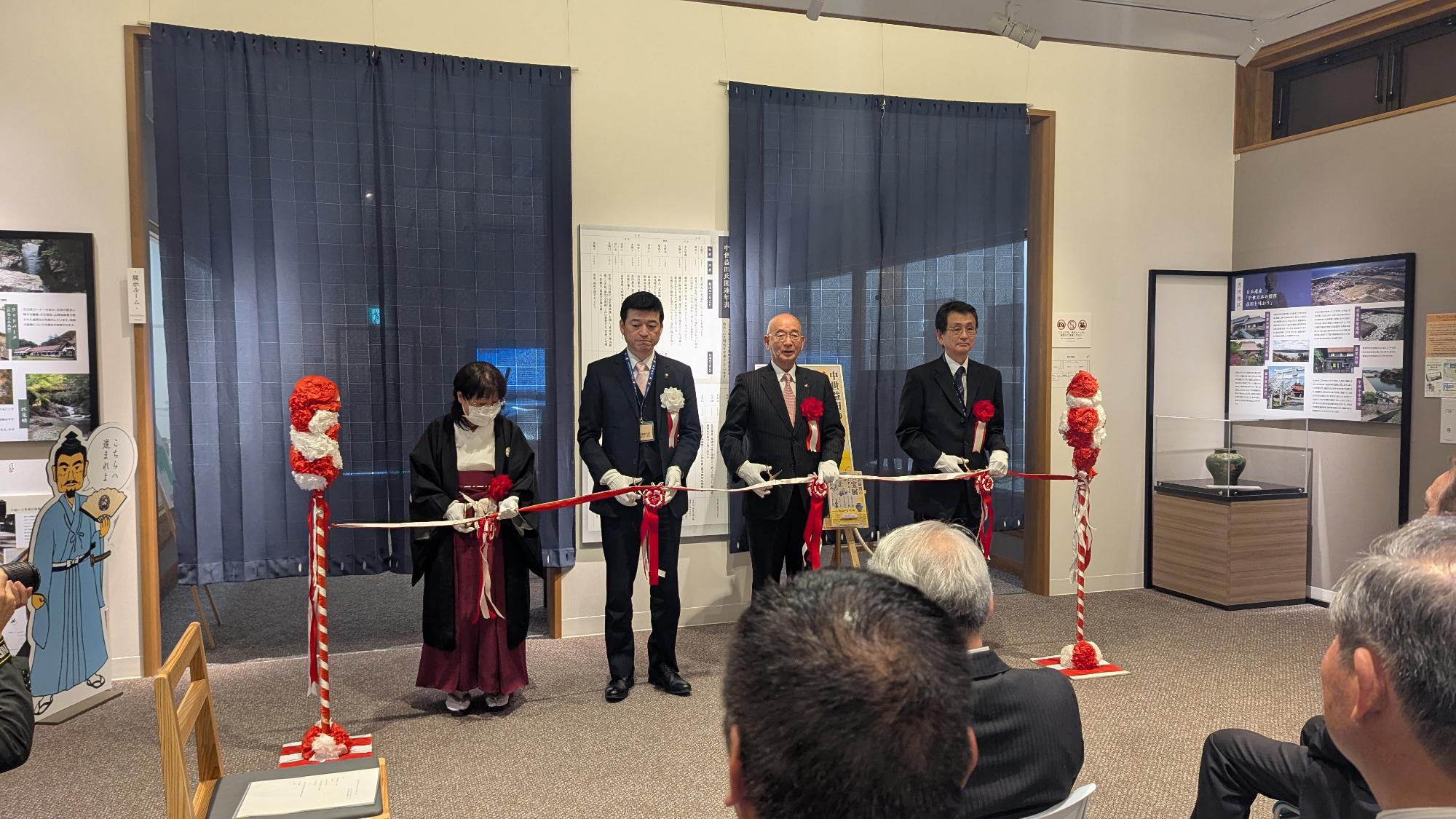 益田市立歴史文化交流館「れきしーな」の「中世益田の至宝展」の内覧会のテープカット(左から、出品者代表の豊田神社の難波光恵宮司、益田市の山本浩章市長、萩市の田中文夫市長、島根県立石見美術館の的野克之館長)
