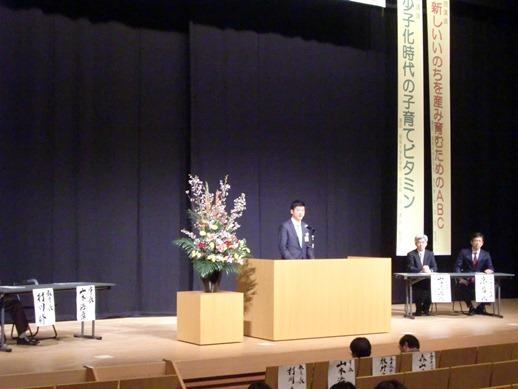 周産期医療講演会の壇上で市長が挨拶している様子の写真