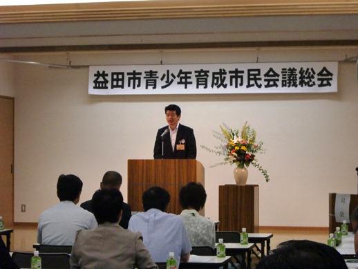 益田市青少年育成市民会議総会の壇上で挨拶をする市長と耳を傾ける参加者たちの写真