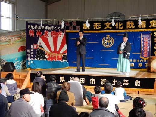 種神楽保存会新春神楽鑑賞会のステージで挨拶を述べる市長と耳を傾ける観客らの写真