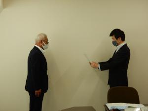 山本市長より末成弘明会長に対し、諮問書を手渡す様子の写真
