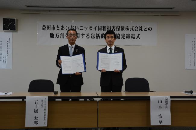 益田市長とあいおいニッセイ同和損害保険株式会社島根支店長が締結書をそれぞれ持っている写真