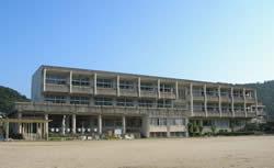青空の下に3階建ての校舎と広い校庭が広がる益田小学校の外観の写真