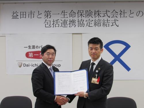 第一生命保険株式会社島根支社長と益田市長が締結書を一緒に持って握手している写真