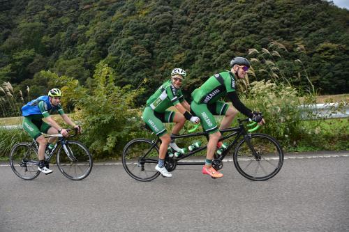 タンデムとロードバイクで坂道を登る選手たちの練習風景