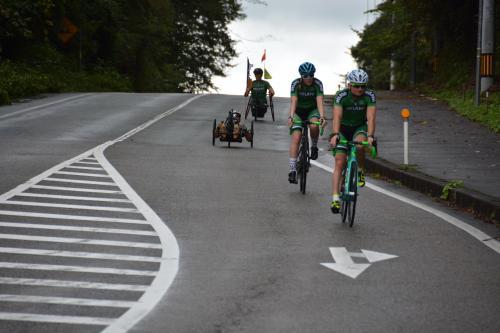ハンドバイクとロードバイクで坂道を下る選手たちの練習風景