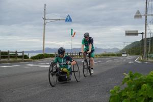 道路を車椅子と自転車で並んで走る選手の様子