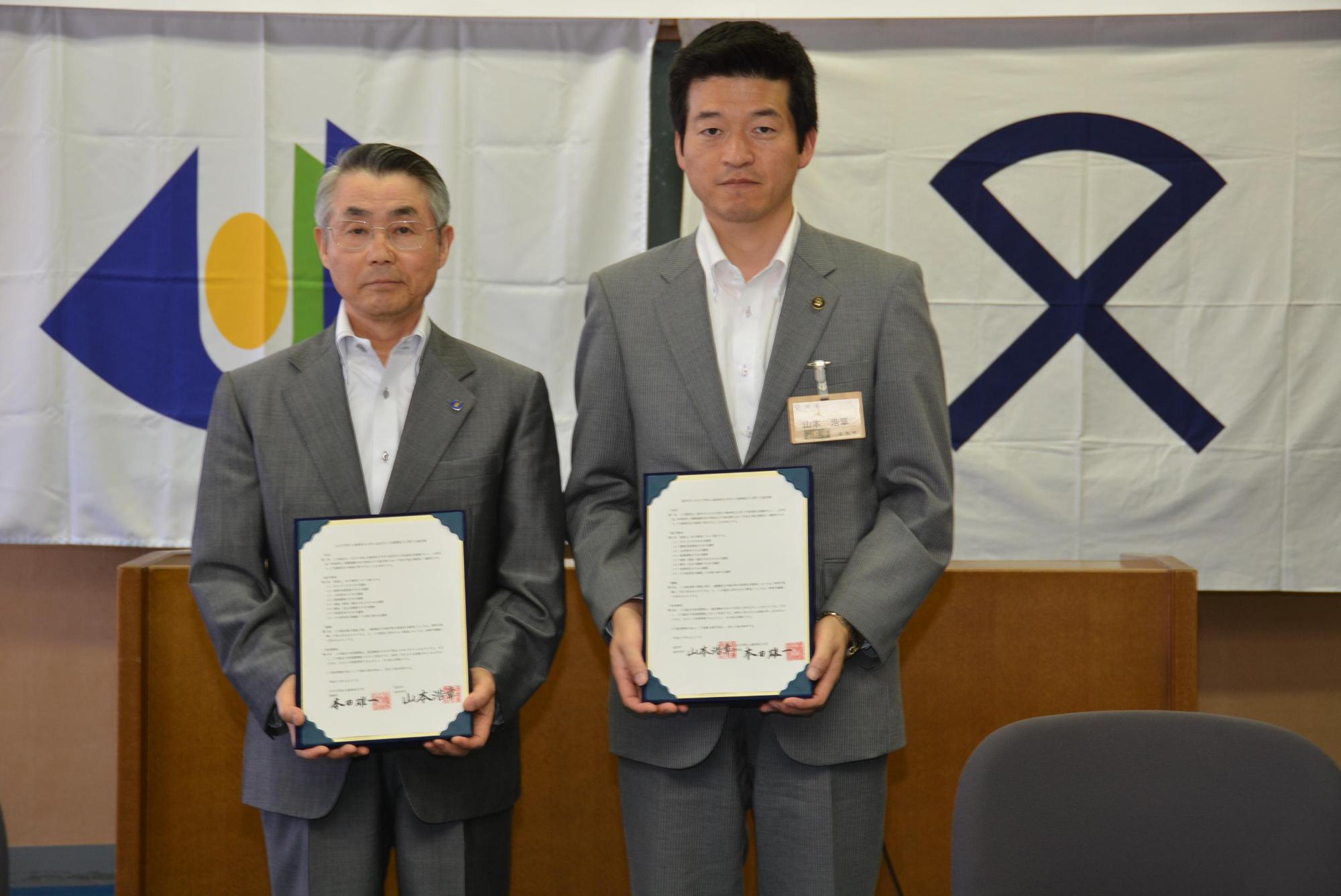市長と島根県立大学理事長が調印書をそれぞれ持っている写真