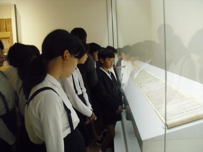 展示物の巻物を見学する小学生の様子の写真
