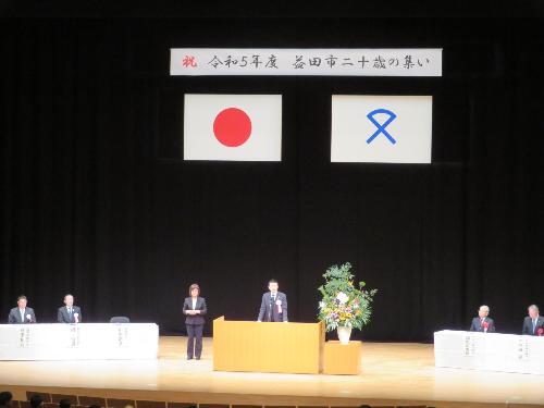 グラントワ大ホール壇上で集いに集まった市民らの前で挨拶をしている市長の写真