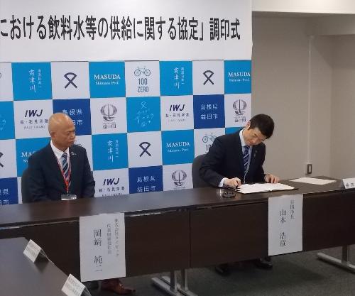 市役所大会議室で協定書に調印している市長の写真