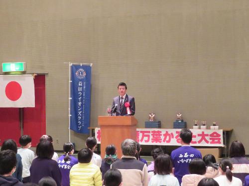 市民学習センター多目的ホールで演台の前に立ち参加者や選手らの前で挨拶をしている市長の写真
