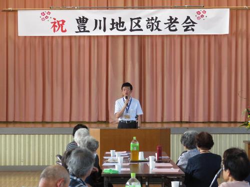 豊川小学校体育館で敬老会に集まった市民の方々にあいさつをしている市長の写真