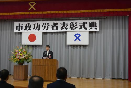 人権センター多目的ホールで壇上から市政功労者らに祝辞を述べている市長の写真