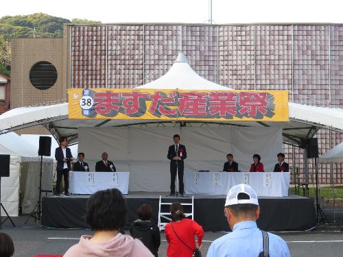 市民学習センター駐車場特設ステージ上でまつり参加者らに挨拶をしている市長の写真