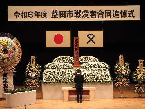 グラントワ小ホールの壇上で戦没者に追悼の献花を行っている市長の写真