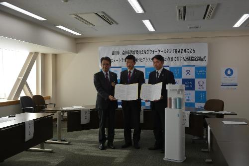 市長と教育長とウォータースタンド株式会社の代表者が協定締結書を持って記念撮影している様子