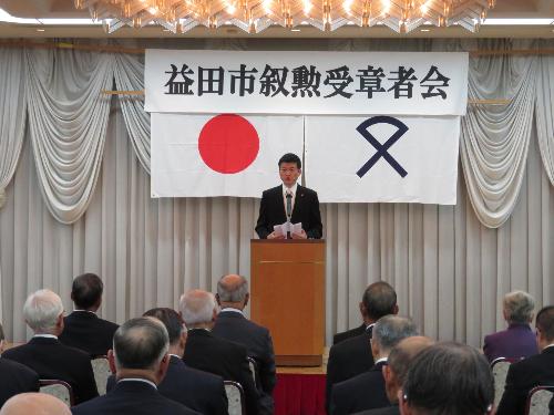 三好家の広間で叙勲受章者会のメンバーらの前で挨拶をしている市長の写真