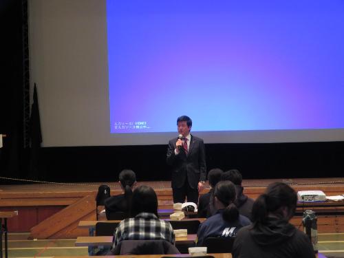 市民学習センター多目的ホールで教室に集まった児童生徒らの前で挨拶をしている市長の写真