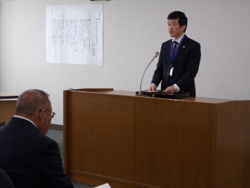 市役所大会議室で演台の前に立ち交通指導員らに委嘱の挨拶をしている市長の写真