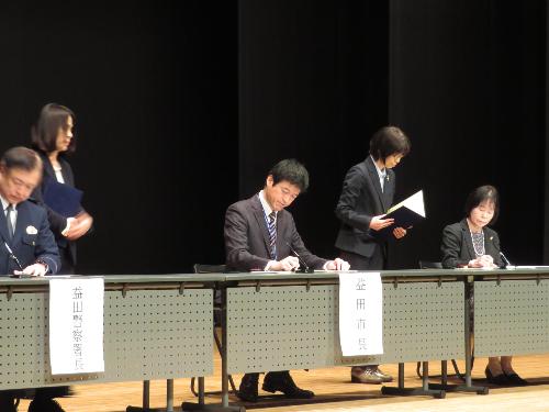 グラントワ小ホール壇上で協定締結書に署名している市長の写真