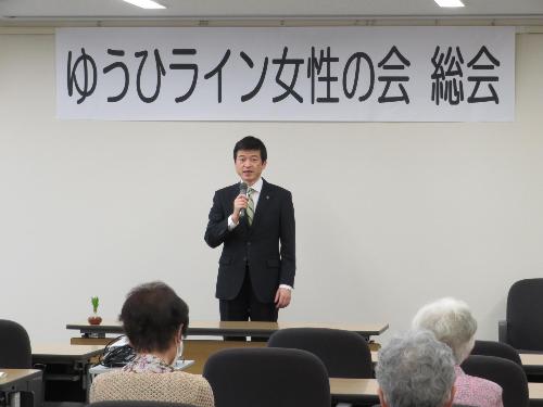 市役所大会議室で会員メンバーらに挨拶をしている市長の写真