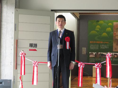 須佐歴史民俗資料館ホールで内覧会出席者らに祝辞を述べている市長の写真