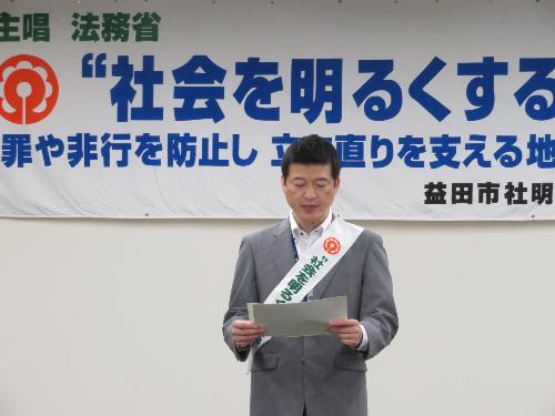 市役所大会議室で伝達式垂れ幕の前で参加者らに挨拶をしている市長の写真