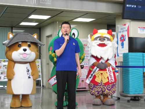 萩・石見空港出発ロビーで近隣市のゆるキャラたちと一緒に大阪便運航初日についてお祝いの言葉を述べている市長の写真
