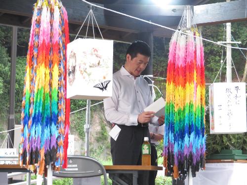 豊川地区で会場に設けられた壇上の上で追悼文を読み上げている市長の写真