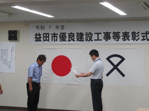 市役所大会議室で表彰企業に表彰状を読み上げている市長の写真