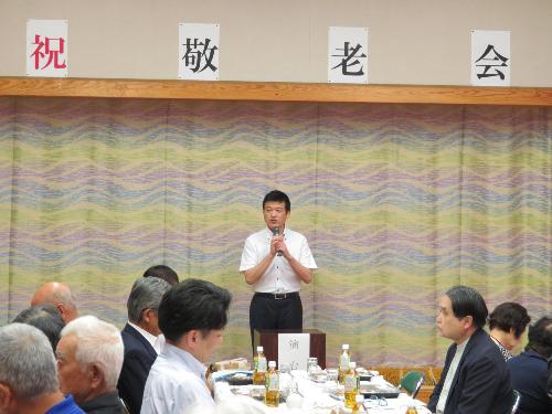 白上コミュニティセンターで敬老会参加者らに祝辞を述べている市長の写真