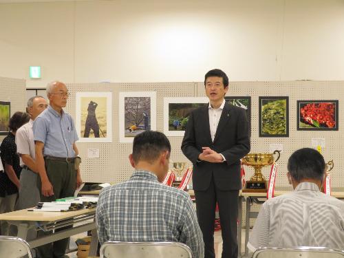 キヌヤ益田ショッピングセンター2階で行われた表彰式に参加した受章者らに挨拶をしている市長の写真