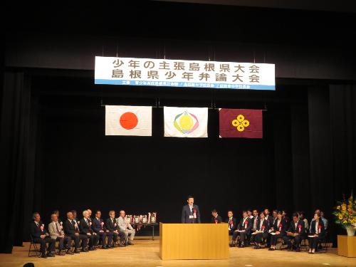 グラントワ小ホール壇上で大会出席者らに挨拶をしている市長の写真