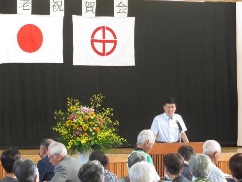 小野中学校屋内運動場で敬老会に参加した出席者らに祝辞を述べている市長の写真