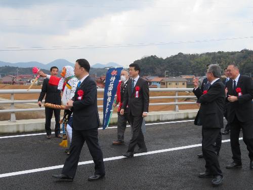 開通した道路を丸山志麻県知事らとともに歩いている市長の写真
