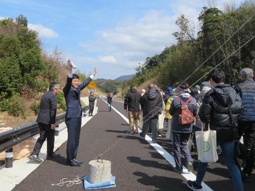 プレイベントで開通前の道路をウォーキングする市民らを見送る市長の写真