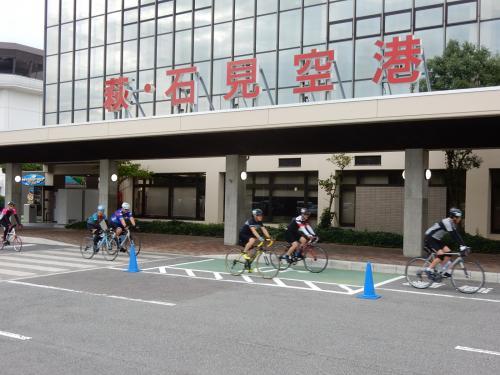 萩・石見空港前を駆け抜けていくロードバイクの選手たちの写真