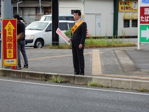 交通安全啓発運動にてプラカードを手に道路わきに立つ市長の写真