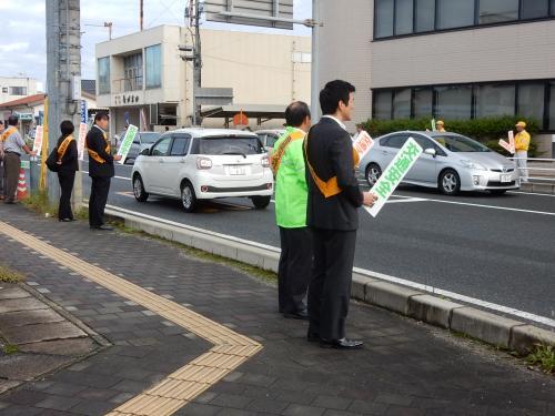 交通安全啓発運動にてプラカードを持ち道路わきに立つ市長と指導員らの写真
