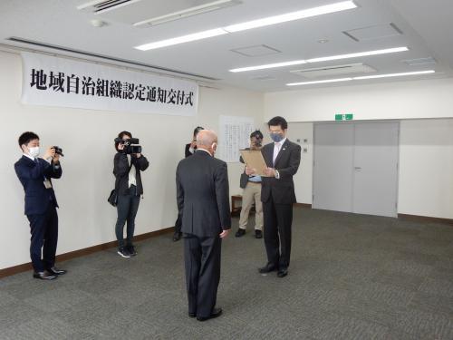自治組織認定書交付式にて男性に認定書を交付している様子の写真
