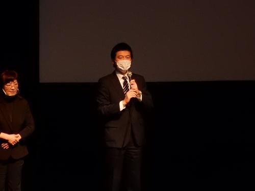 映画上映会にてマイクを持って挨拶する市長の写真