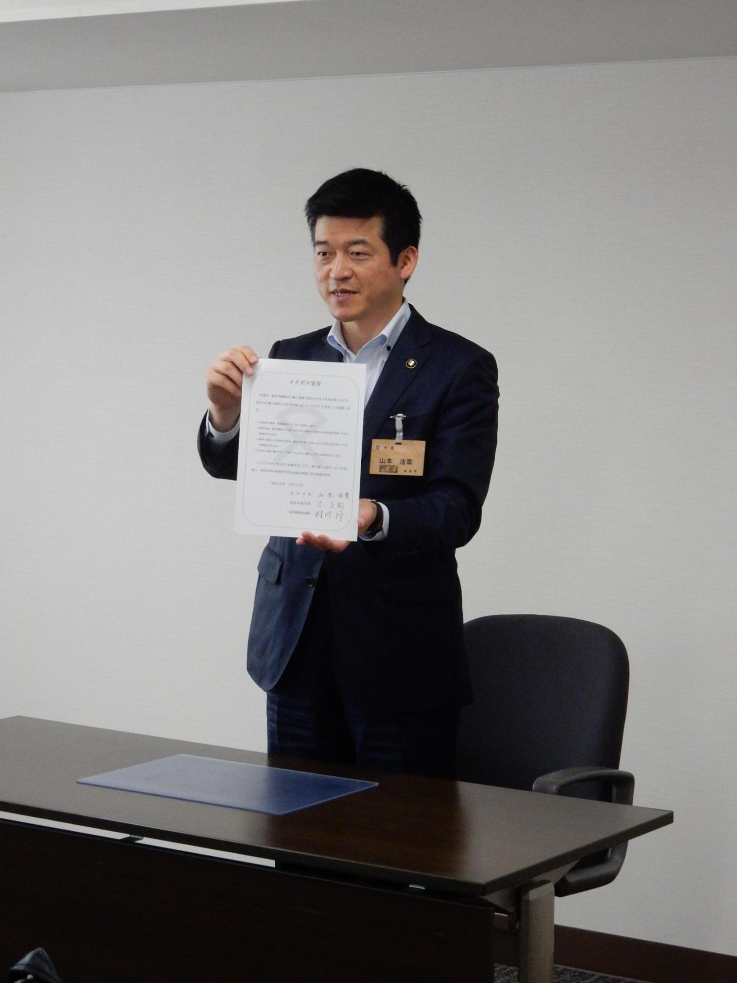 イクボス宣言の書類を掲げる市長の写真
