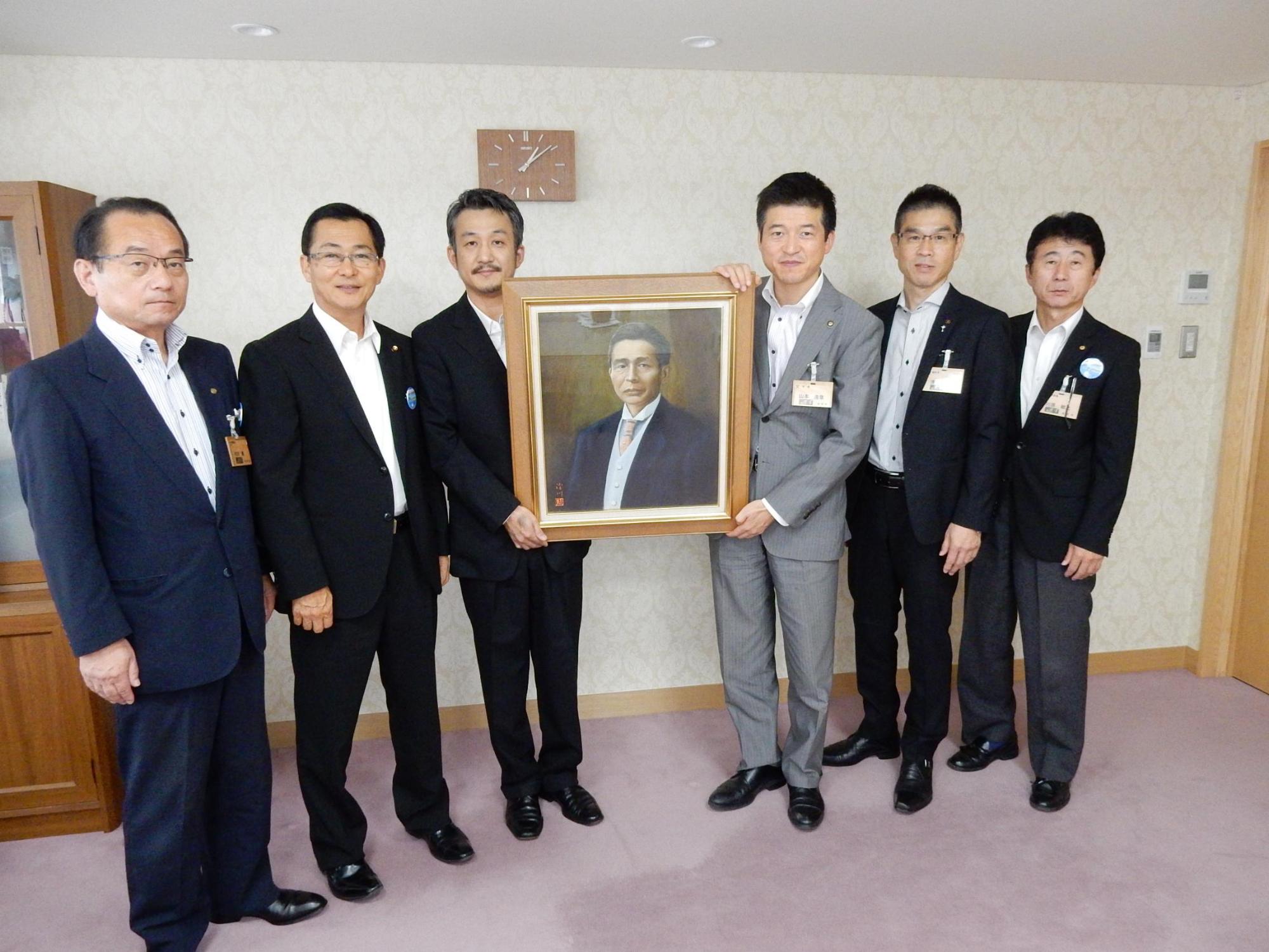 澄川歯科医院より寄贈された絵画と共に関係者らと市長の記念写真