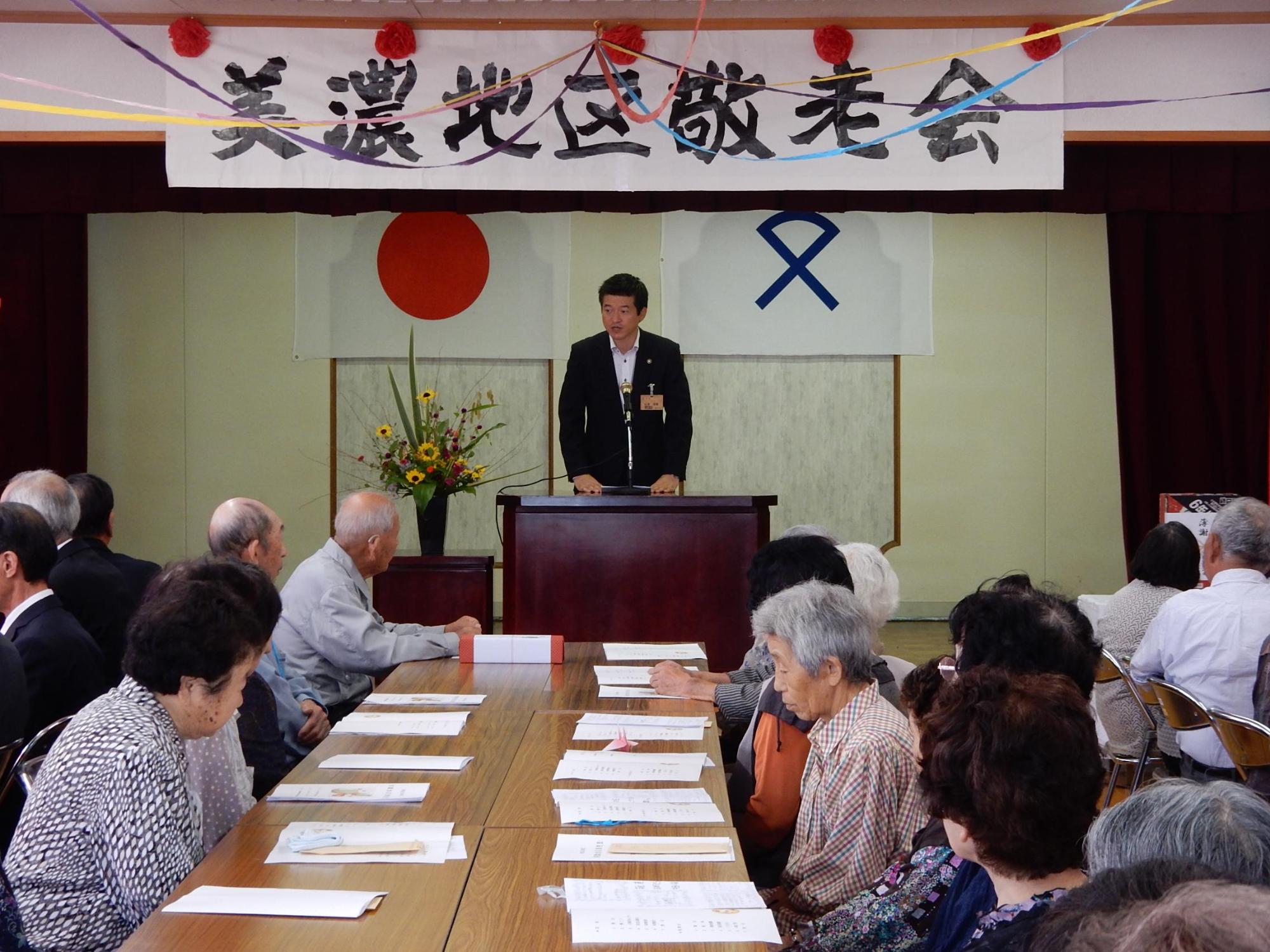 美濃地区敬老会にて挨拶を述べる市長の写真と傾聴する出席者らの写真