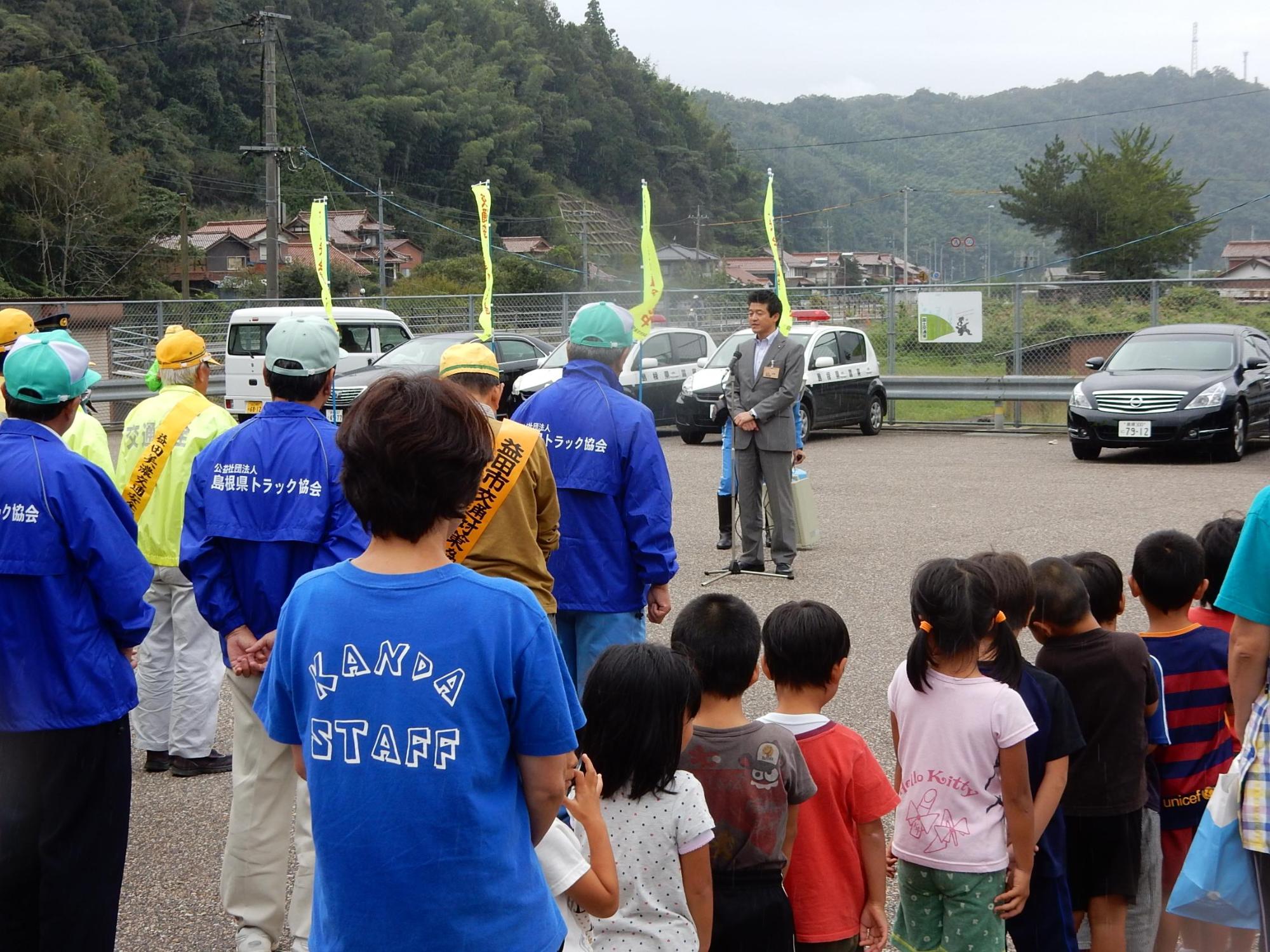 秋の交通安全運動にて参加者らの前で言葉を述べる市長の写真