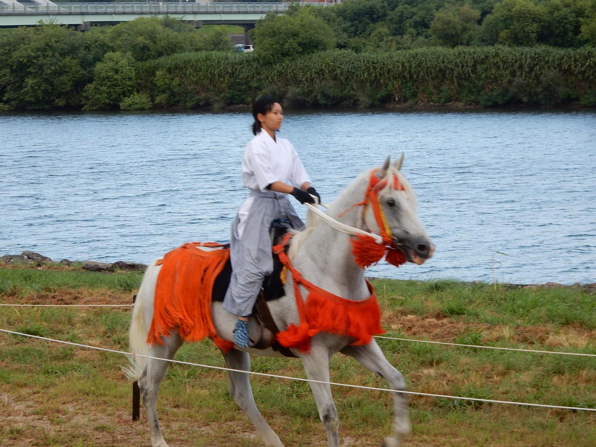 馬にまたがりやぶさめ行事に参加する様子の写真
